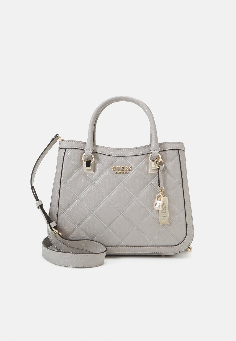 Sac à main matelassé gris Guess avec doubles poignées, bandoulière amovible, ferrures dorées et breloque logo sur fond uni.