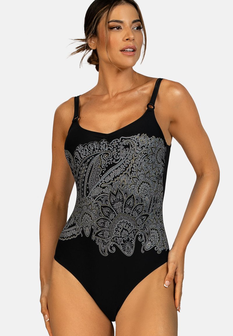 Kobieta ubrana w czarny jednoczęściowy strój kąpielowy z szarymi, skomplikowanymi wzorami paisley i kwiatowymi, z regulowanymi ramiączkami na ramionach, pozująca z ręką na biodrze.