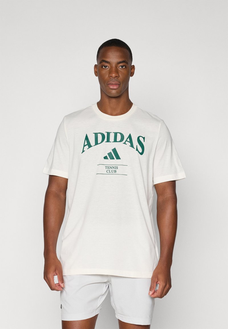 T-shirt de algodão branca com o logótipo verde "ADIDAS" e o texto "TENNIS CLUB". Mangas curtas com decote redondo e um corte descontraído.