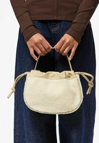 Borsa color crema con un corpo testurizzato e morbido e parte superiore liscia color tan. Presenta un design arricciato e due accenti di manico annodati.