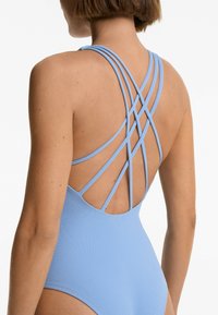 Blue one-piece swimsuit with a textured fabric. Features wide crisscross straps at the back and a scoop neckline design.
