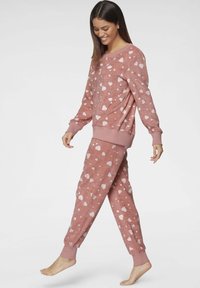 Pink sweatshirt and joggers with white heart patterns, featuring ribbed cuffs and waistband, soft texture, and loose fit.