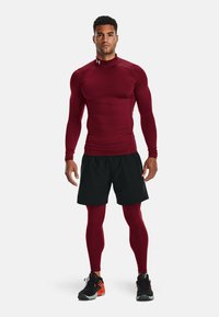 Maronfarvet tætsiddende langærmet skjorte og sorte shorts, parret med maronfarvede leggings og sorte sko med orange detaljer. Enkel, atletisk stil.