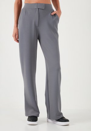 Gray, wide-leg trousers made of textured fabric, featuring a belt loop waist, side pockets, and a smooth finish. Styled with black sneakers.