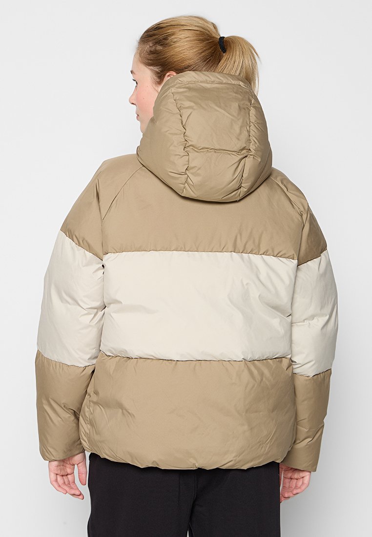 Beżowa i kremowa kurtka puchowa z kapturem, z pikowaną strukturą i masywną sylwetką.