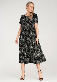 Black floral dress with short sleeves, featuring white embroidered flower patterns and a flowing silhouette, falls below the knee.