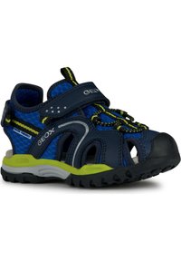 Sandalias azul marino con malla transpirable, correa ajustable y acentos verdes brillantes. Presenta una suela de goma con textura para mayor agarre.