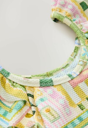 Višebojni uzorčasti materijal s geometrijskim oblicima u ružičastoj, žutoj, zelenoj i plavoj boji s teksturiranim završetkom i okruglim izrezom.