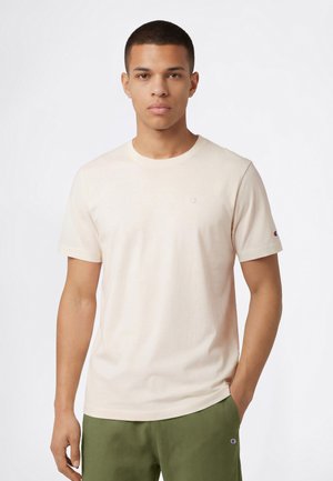 T-shirt beige chiaro con scollo girocollo, maniche corte, realizzata in cotone liscio. Presenta un piccolo logo ricamato sul petto e sulla manica.