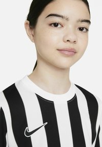Das Nike-Trikot verfügt über schwarz-weiß gestreifte vertikale Streifen, einen runden Ausschnitt und das weiße Nike-Logo auf der linken Brust. Glatte Stofftextur.