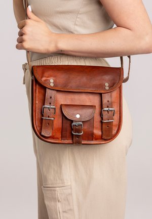 Brun læder crossbody taske med klap, justerbar strop, to frontspænder og en lille forlommer. Glat overflade med sølv accenter.