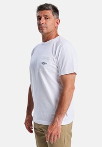 Hvid kortærmet T-shirt i bomuld med en brystlomme. Har et lille logo og en rund halsudskæring. Stoffet virker glat og blødt.