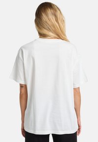 Hvid bomulds T-shirt med afslappet pasform, korte ærmer og rund halsudskæring. Glat tekstur og enkel design, ingen synlige prints eller mønstre.