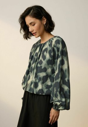 Lockere Bluse mit einem grünen und marineblauen Leopardenmuster, gerafftem Ausschnitt und langen, puffigen Ärmeln. Hergestellt aus leichtem Stoff.