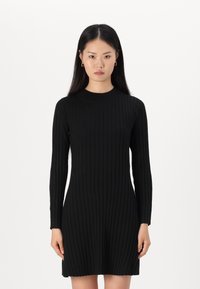Vestido preto de malha canelada com mangas longas, decote redondo e forma ajustada, apresentando uma textura suave e um comprimento sutil acima do joelho.