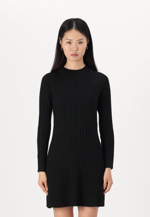Robe tricotée côtelée noire avec des manches longues, un col rond et une forme ajustée, présentant une texture lisse et une longueur subtile au-dessus du genou.
