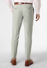 Lichtgroene op maat gemaakte broek met een textuurafwerking, slim fit en achterzakken, gecombineerd met bruine leren schoenen en een wit shirt.