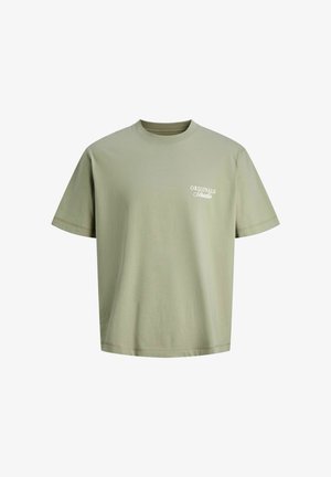 Svjetlozelena majica kratkih rukava s okruglim izrezom s malim bijelim natpisom "ORIGINALS Studio" na lijevoj strani prsnog koša.