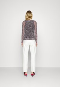 Top trasparente a maniche lunghe con un motivo multicolore, abbinato a pantaloni bianchi a vita alta e scarpe con tacco rosa. Design semplice e moderno.