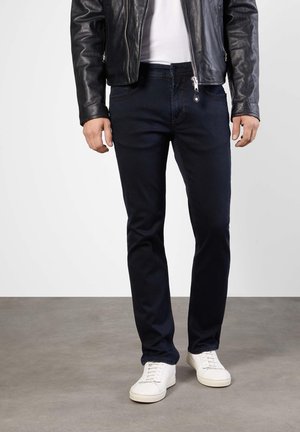 Marineblauwe jeans van denim, met een slim fit ontwerp, voorzakken en een ritssluiting, gecombineerd met witte sneakers en een zwart leren jack.