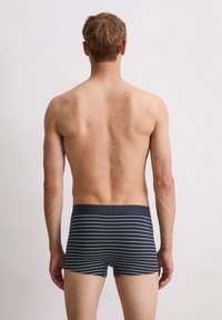 Bóxers a rayas en blanco y negro con una suave cinturilla elástica, mostrados desde una vista trasera, de estilo ajustado, con un largo de pierna corto.