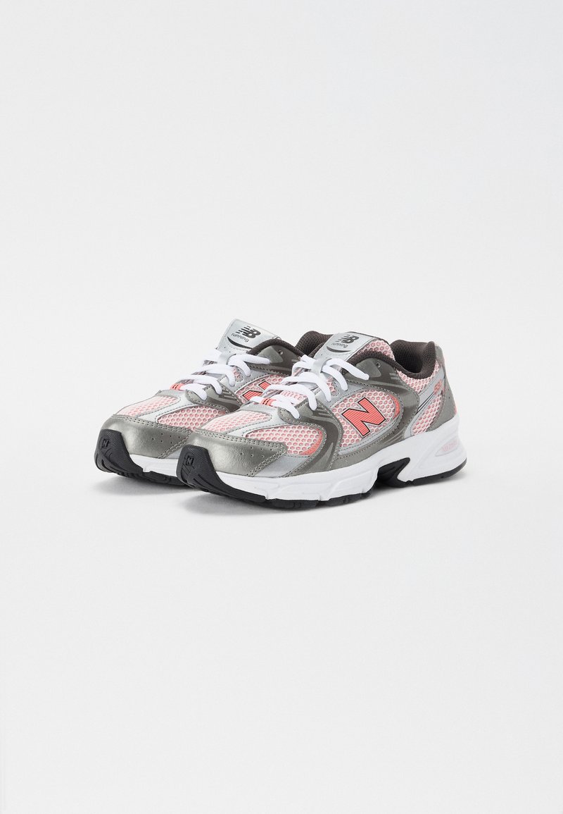 Graue und rosa Sportschuhe mit einem Obermaterial aus Mesh, gepolstertem Kragen und weißen Schnürsenkeln. Gummisohle mit strukturiertem Grip. New Balance-Logo sichtbar.