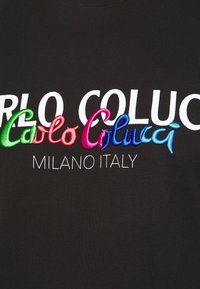 Camiseta de algodón negra con texto bordado en blanco y colorido: "CARLO COLUCCI" y "MILANO ITALY". Textura suave, diseño de cuello redondo.