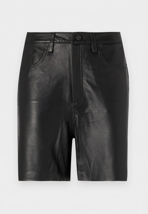 Haut sans manches noir avec des détails en dentelle au col en V, associé à un short bleu marine et un petit sac à main crème. Mannequin portant des ballerines noires.