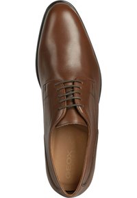 Chaussure en cuir marron à lacets avec une finition lisse, bout arrondi et détails de couture subtils. Présente une semelle intérieure marquée et une fine semelle noire.