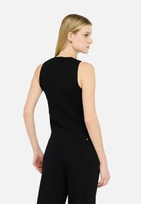 Black sleeveless top made of a soft, stretchy fabric. It has a fitted silhouette and a crew neckline, with minimal seams and no embellishments.