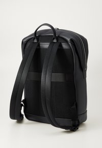 Black backpack with a smooth leather exterior, mesh back, and padded straps. Features a zippered closure and minimal hardware accents.