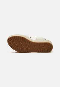 Sandal espadrille beige con una suola intermedia in juta e una suola esterna in gomma. Presenta una suola marrone testurizzata con battistrada a motivo per una migliore aderenza.