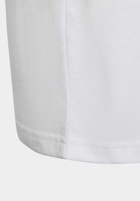 Camiseta de algodón blanca con una textura suave, dobladillo redondeado y costuras bien terminadas. Diseño simple, sin patrones ni acentos adicionales visibles.