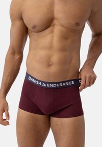 Burgundy kalsonger med marinblå elastisk midjeband märkt "DANISH ENDURANCE." Tillverkade av mjukt tyg, designade för komfort och passform.