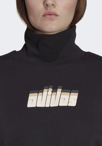 Felpa nera con collo alto, caratterizzata da un logo degradé in beige e crema, con una texture morbida e liscia e un design aderente.