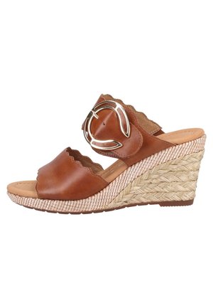 Sandalo con zeppa in pelle marrone con bordi smerlati, grande fibbia rotonda color oro e tacco platform in paglia intrecciata.