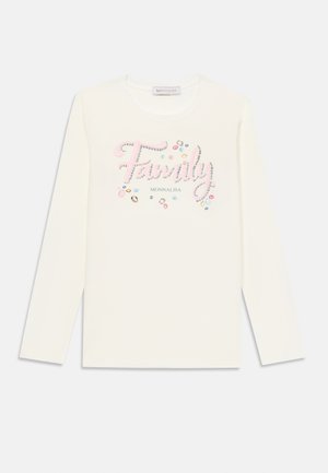 Crème shirt met lange mouwen met "Familie" in het roze, afgewerkt met strassteentjes en kleurrijke edelstenen. Zachte stof met een ronde halslijn.