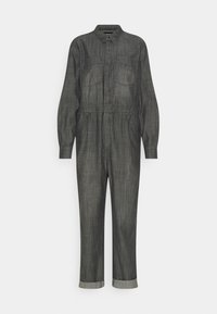 Mono de mezclilla gris oscuro con mangas largas, dos bolsillos en el pecho, cintura elástica y puños enrollados en los tobillos, con cuello abotonado.