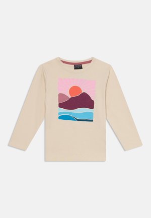 Chemise beige à manches longues avec un graphique coloré d'un soleil rouge, des montagnes violettes et des vagues bleues sur le devant.
