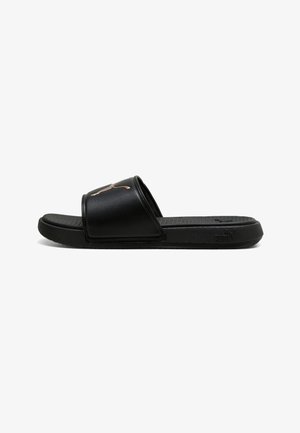 Schwarze Slide-Sandale mit gepolsterter Sohle und breitem Riemen mit metallischem Puma-Logo, seitlich auf weißem Hintergrund gezeigt.