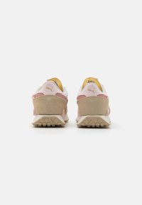 Sneakers con una toma superiore in rete bianca, accenti in suede rosa e foderatura gialla. Suola piatta in gomma beige con scanalature per la trazione. Logo Puma sul tallone.