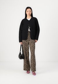 Black quilted jacket with button closures, paired with leopard print wide-leg trousers. Accessories include a small black bag and purple sandals.