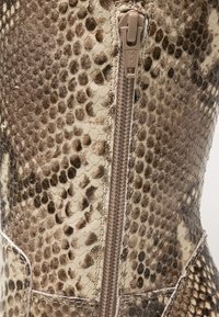 Brown and cream snake-print leather boot featuring a central zipper closure and textured pattern on the shaft.