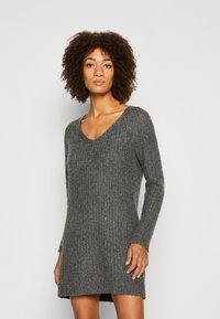 Vestido de punto gris con escote en V y mangas largas, que presenta un acabado texturizado y una abertura lateral para mayor facilidad de movimiento.