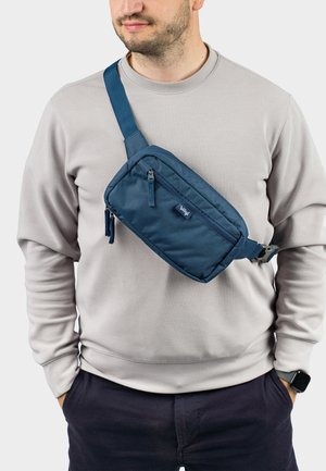 Borsa a tracolla in nylon blu navy indossata sul petto, con due scomparti con zip e una robusta tracolla regolabile, design razionalizzato.