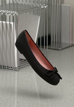 Ballerine nere con una texture liscia, dettaglio a fiocco davanti e interno rosso a contrasto. Design minimalista, forma della punta arrotondata.