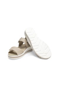 Beige leather sandals with an adjustable strap. Thick white rubber sole, textured bottom, and minimalist design with contrasting stripes.