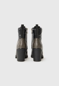 Black leather ankle boots with a textured brown heel panel featuring a logo pattern. Zipper closure and contrasting stitching detail.