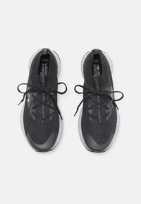 Mustat neulotut urheilukengät, joissa on teksturoidut päälliset, pyöreät kärjet ja mustat nauhat; niissä on pilkullinen valkoinen välikenkä ja logomerkit kieliosassa.