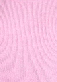 Ružový sveter s rebrovanou textúrou, ktorý má jemný pocit na dotyk a okrúhly výstrih, zobrazuje pravidelný vzor s vertikálnymi pruhmi. Bez viditeľného kovania.